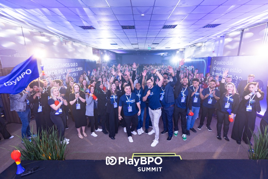 Equipe PlayBPO e participantes reunidos no palco da plenária, com bandeira azul da PlayBPO erguida, na celebração de encerramento do PlayBPO Summit 2025
